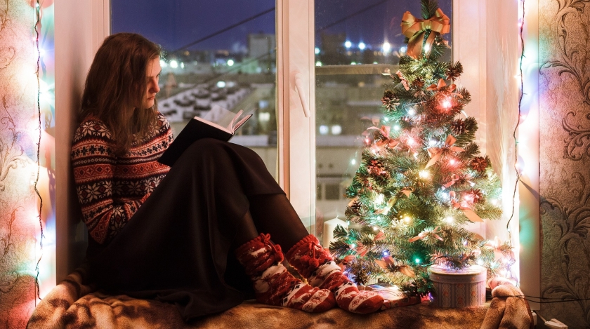 Teen girl reading next to a Christmas tree